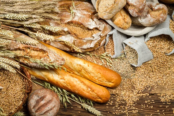 Various kinds of whole wheat bread on old wooden table — Stock Photo, Image