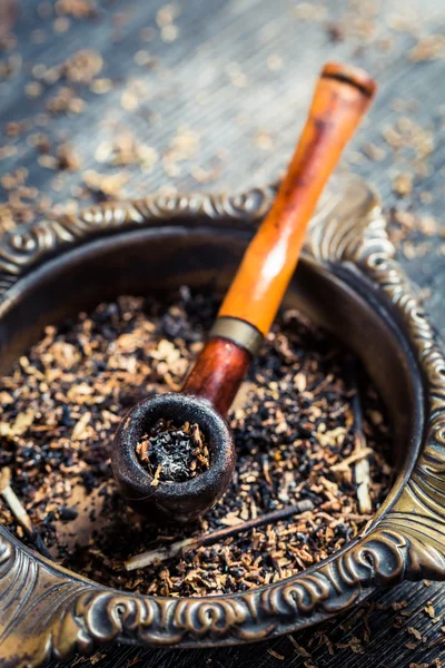 Old wooden pipe in an ashtray — Stock Photo, Image