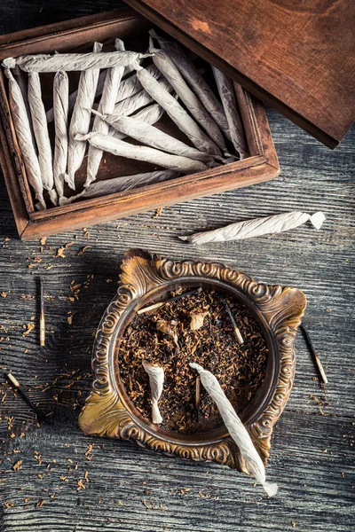 Сигареты в старой деревянной коробке, пепельнице и зажигалке — стоковое фото