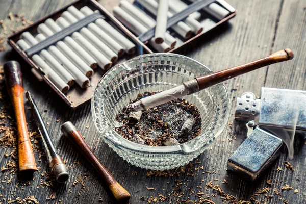 Стеклянная пепельница с тонкими деревянными трубами, сигаретами и более легкой аро — стоковое фото