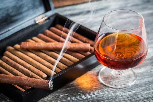 Burning cigar on humidor and cognac — Stock Photo, Image