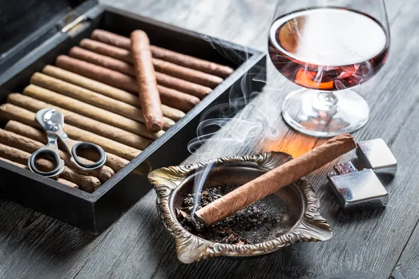 Brinnande cigarr i askkopp och cognac — Stockfoto