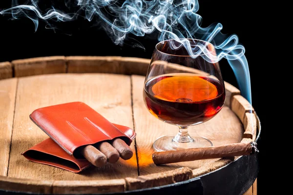 Cognac dans un verre sur tonneau et cigare brûlant — Photo