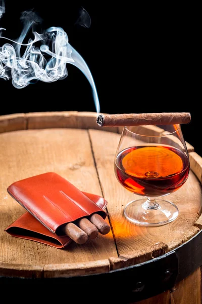 Glass of cognac and cigar on old barrel — Stock Photo, Image