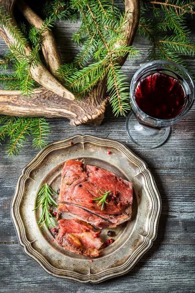 Pièce de venaison servie avec du vin rouge — Photo