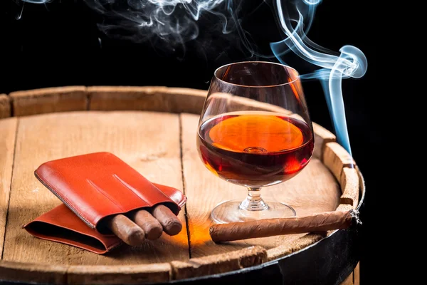 Coñac en un vaso en barril y cigarro en llamas — Foto de Stock