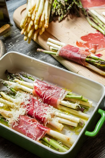 Preparation of asparagus wrapped in Parma ham with cheese — Stock Photo, Image