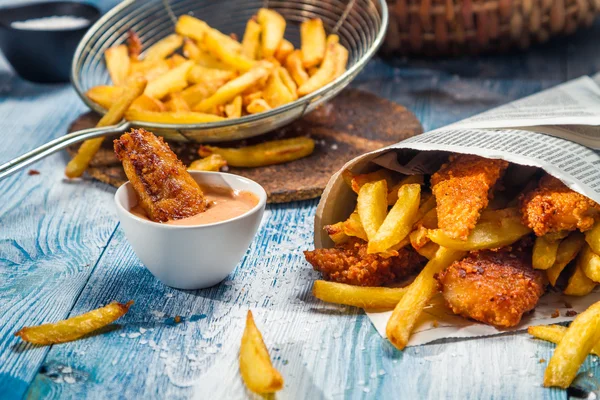 Closeup de peixe e batatas fritas servidos em papel — Fotografia de Stock