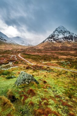 Snow capped mountains and a path in Glencoe clipart