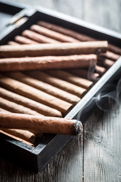 Καπνού αυξάνεται από ένα φλεγόμενο πούρο σε ξύλινα υγραντήρα — Φωτογραφία Αρχείου