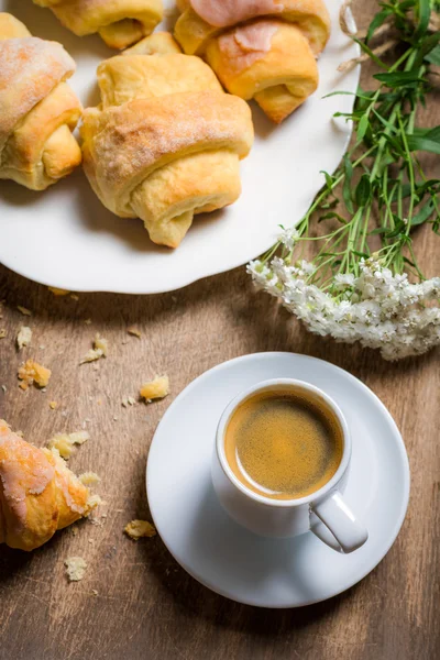 Frukost på sängen med en croissant och blommor — Stockfoto