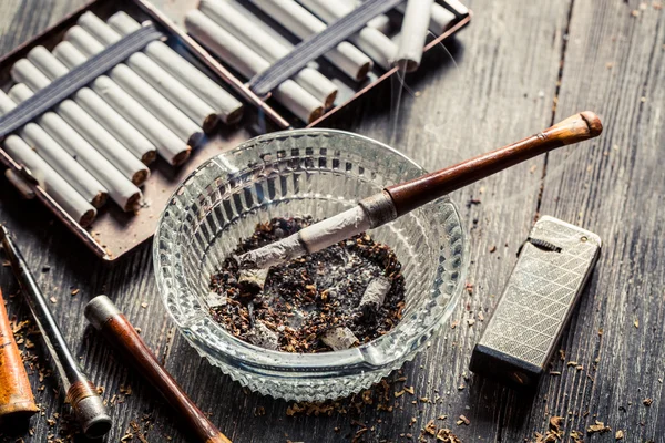 Glass ashtray with thin wooden pipes, cigarettes and lighter aro — Stock Photo, Image