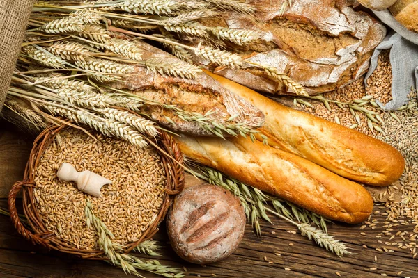 Various kinds of whole wheat bread on old wooden table — Stock Photo, Image