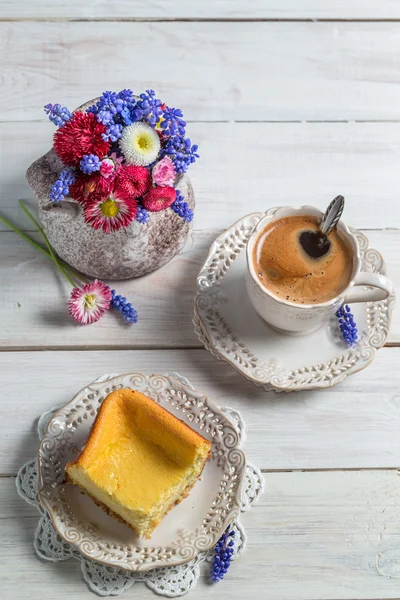 Cheesecake, cup of coffee and spring flowers — Stock Photo, Image