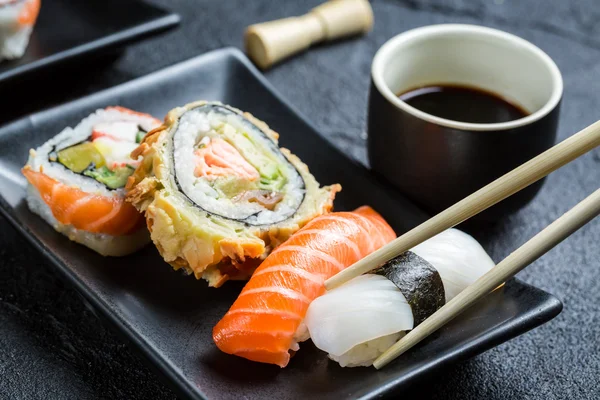 Sushi com molho de soja comido com pauzinhos — Fotografia de Stock