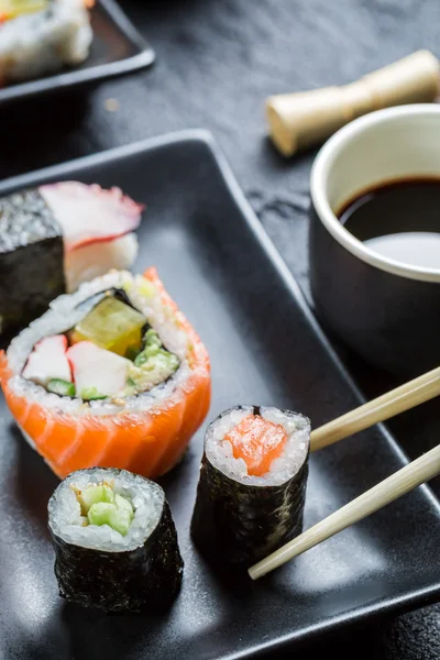 Sushi on black ceramic eaten with chopsticks — Stock Photo, Image