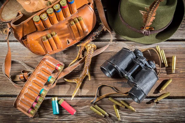 Väska med kulor, kikare och hatt i en jaktstuga — Stockfoto