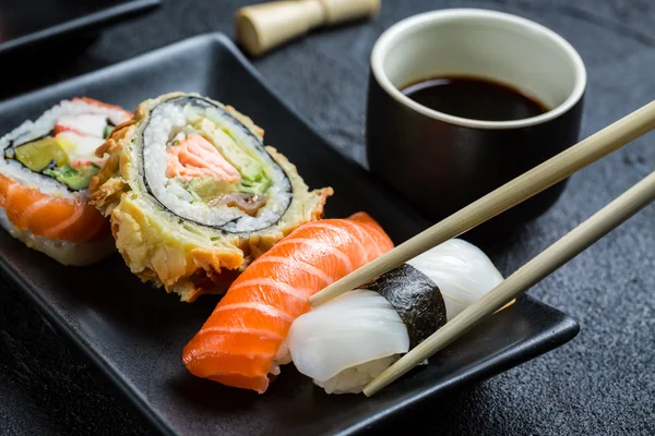 Sushi com molho de soja comido com pauzinhos — Fotografia de Stock