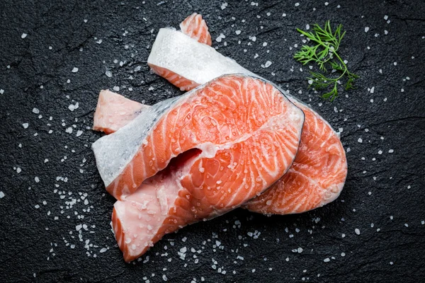 Fresh raw salmon on black rock — Stock Photo, Image