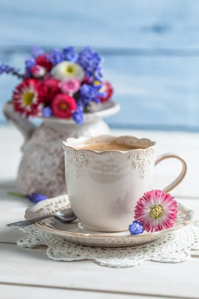 Closeup sedmikrásky květin a šálek kávy — Stock fotografie