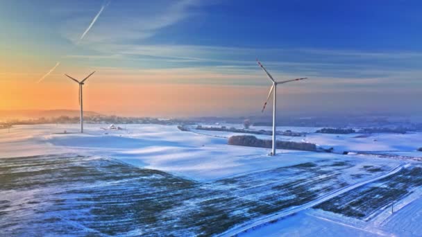 Windkraftanlage auf einem verschneiten Feld bei Sonnenaufgang. Alternative Energien. — Stockvideo