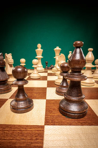 Wooden chess shown in an unusual way on green background.