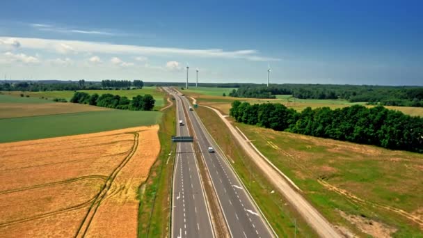 Luchtfoto van gouden veld en windturbines in de buurt van de snelweg. — Stockvideo