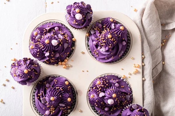 脂肪の木曜日のための紫色のクリームで作られたおいしいカップケーキ ベーキングトレイに黄金のスプリンクルと紫のデザート — ストック写真