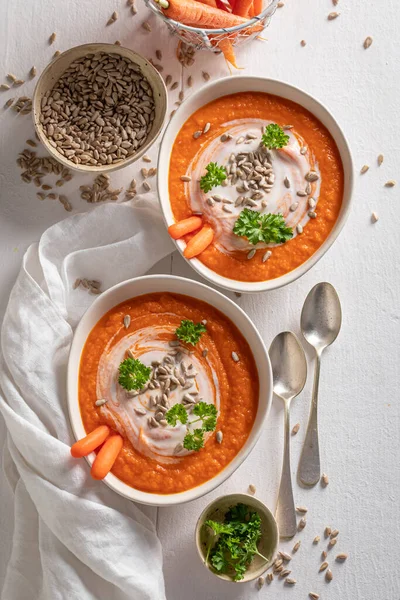 健康的な春の前菜としておいしいクリーミーなニンジンスープ 白鉢の中にハーブや種を入れたニンジンスープ — ストック写真