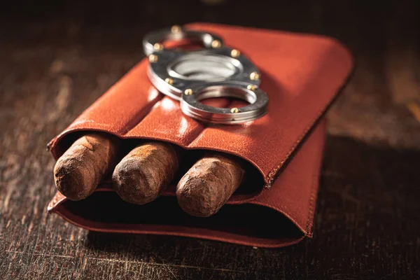 木制桌子上皮制容器里的三支雪茄和一把刀 — 图库照片