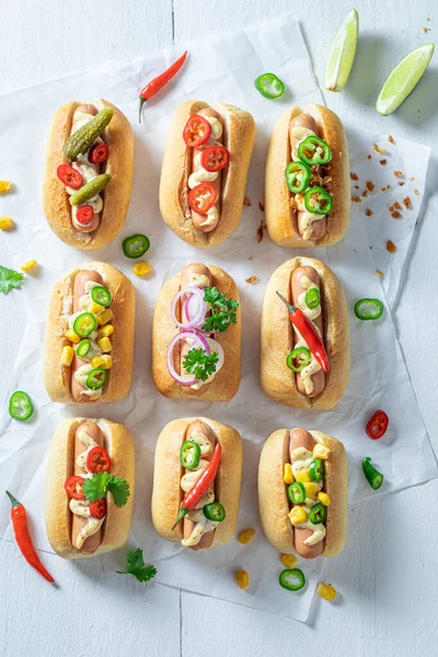 Hot and homemade mini hot dogs with sausage and sauce. Mini hot dogs with spicy sausage and mustard.