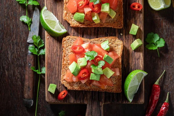 Vegetarian and hot toasts with avocado, tomatoes and coriander. Toasts as a healthy appetizer.
