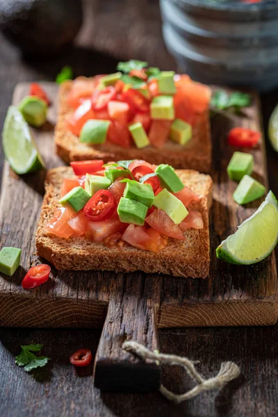 Tasty and fresh toasts with avocado, tomatoes and coriander. Crunchy toasts as a quick snack.