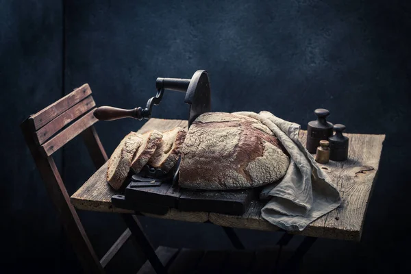 Homemade and rustic loaf of bread with on old slicer. A loaf of bread on a crumb slicer.