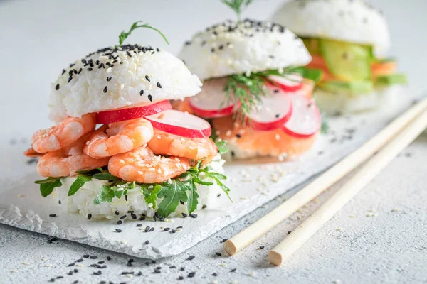 Delicious and exquisite sushi burger with shrimps and fish as Japanese appetizers. Sushi with seafood made in unique way.