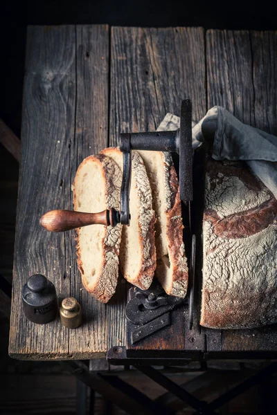 Crunchy and fresh loaf of bread with on old slicer. A loaf of bread on a crumb slicer.