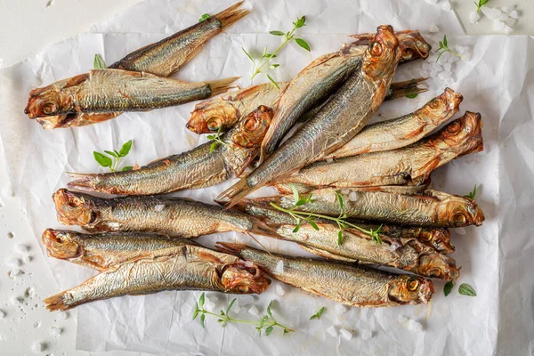 Salty smoked sprats as appetizer by the sea. Smoked fish marinated with salt and herbs.