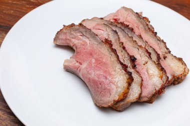 Tütsülenmiş ve ızgara bifteği beyaz tabakta dilimlenmiş. Biftek dilimlenmiş. Batı geleneksel yemekleri. 