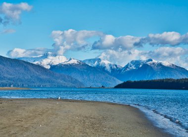Gustavus 'taki Güneydoğu Alaska plajı dağlara ilk kar yağışı ve kabarık bulutlarla.