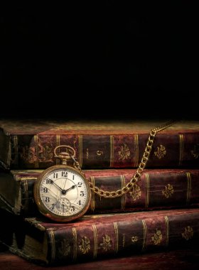 Antika cep saati ve siyah arkaplan üzerine eski kitaplar.