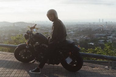 Motosikletli ya da moto binicisi güzel şehir manzarasıyla gezerken poz veriyor. 