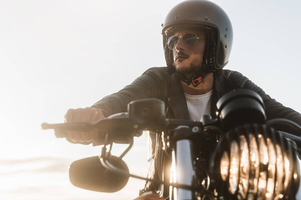 Portrait of biker looking away, sitting on his vintage motorcycle
