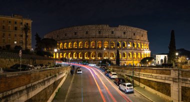 Yakındaki bir yaya köprüsünde geceleri Colosseum 'un bir resmi görülüyor..