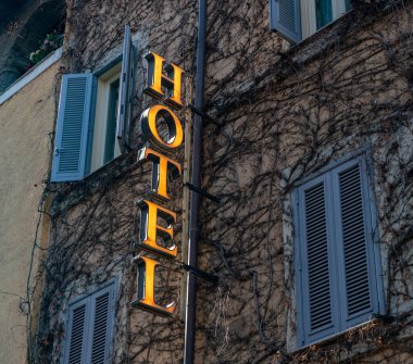 Bir sürü sarmaşıkla dolu bir cephede otel tabelasının resmi..