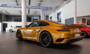Turuncu bir Porsche 911 Turbo S 'nin bir galeride çekilmiş resmi..