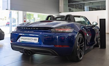 Koyu mavi bir Porsche 718 Boxster 'ın bir galerinin içindeki resmi..
