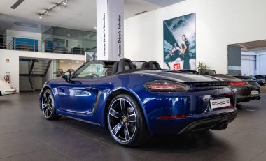 Koyu mavi bir Porsche 718 Boxster 'ın bir galerinin içindeki resmi..