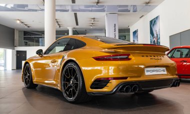 Turuncu bir Porsche 911 Turbo S 'nin bir galeride çekilmiş resmi..