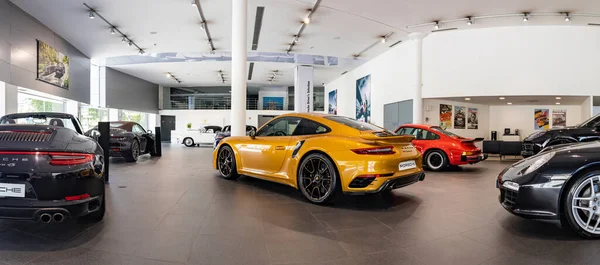 Merkezinde turuncu 911 Turbo S olan bir Porsche bayisinin resmi..