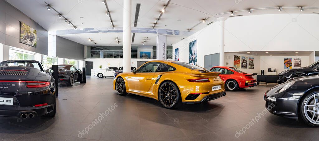 A picture of a Porsche dealership with an orange 911 Turbo S in the center.